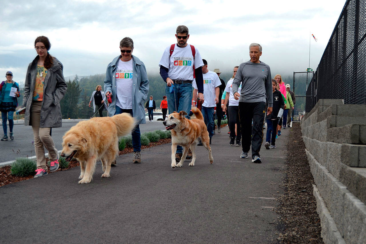Lisa Boulware and Mark Ozias walk with their dogs while talking with Eric Lewis, chief executive officer for Olympic Medical Center during the Sequim Free Clinic’s 2018 Fun Walk. Sequim Gazette file photo by Matthew Nash
