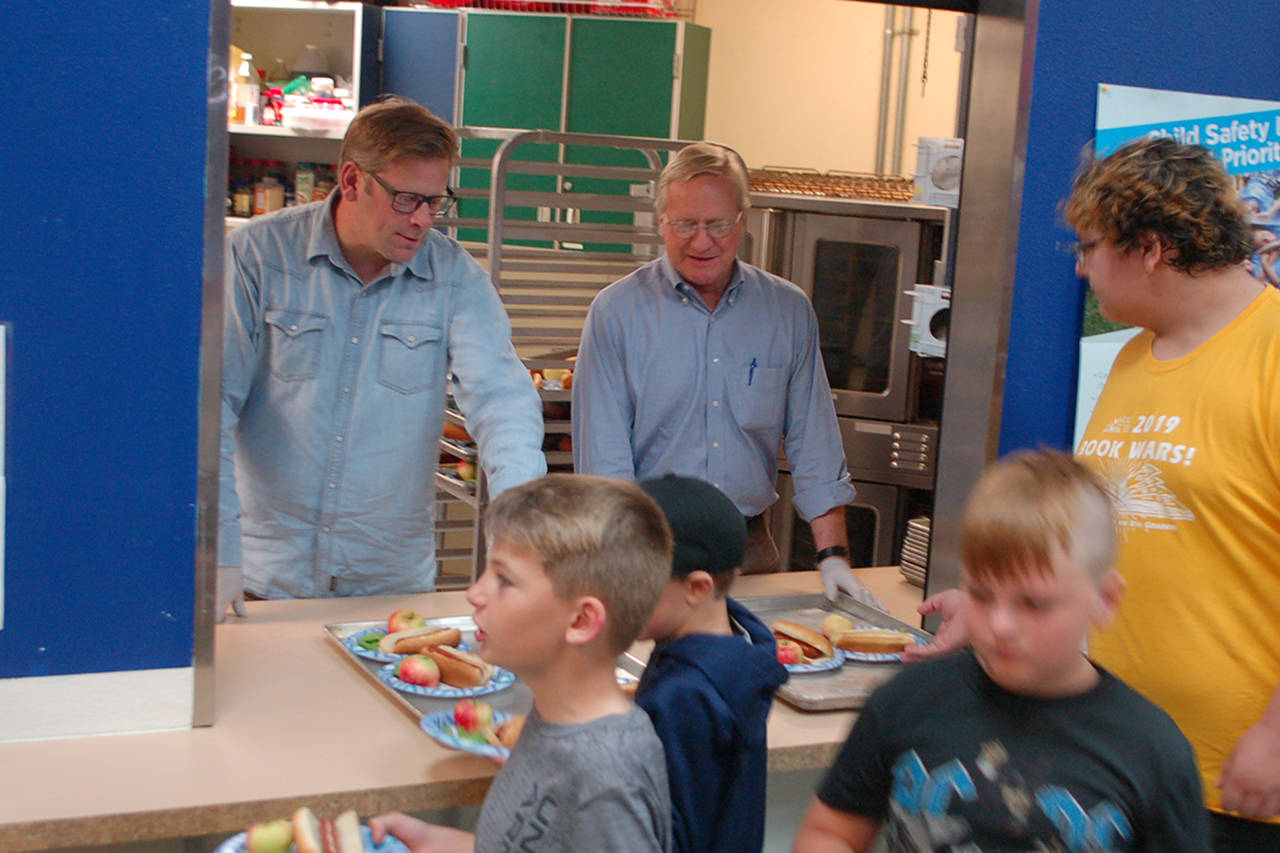 Washington State Reps. Mike Chapman, left, and Steve Tharinger, center, of the 24th legislative district serve lunch for the kids at the Boys & Girls Club in Sequim on Aug. 27. The club serves a free lunch to attendees and to families at several community locations every day during the summer. Sequim Gazette photos by Conor Dowley