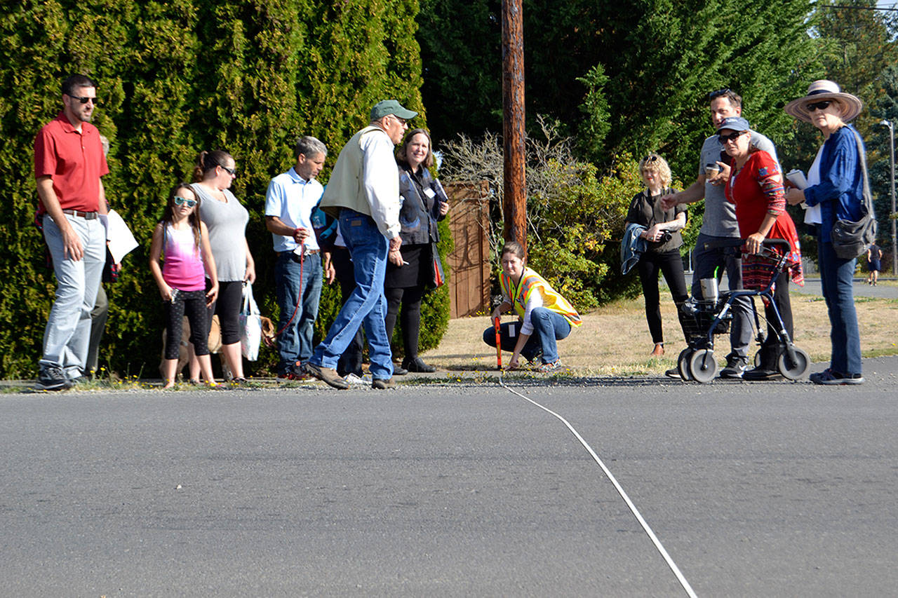 Katie Cole, Sequim associate engineer, measures a roadway as residents and consultants look on during a walking tour for the South Sequim Complete Streets project. Some residents on the tour said downtown neighborhoods are too small for new amenities and increased traffic. Sequim Gazette photos by Matthew Nash