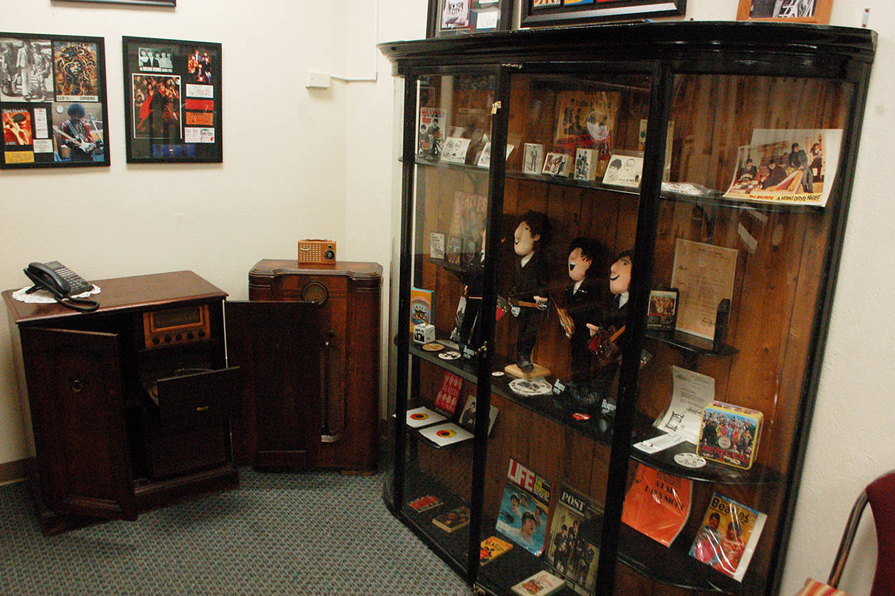 Left, a collection of Beatles memorabilia on display in the KSQM community room, along with classic radios and other musical memorabilia. Collection owner George Dooley, who hosts “Doctor Dee’s Roots of Rock” Friday nights at 8:30 p.m. on KSQM, has what he calls a “significant” rock and roll memorabilia collection that he’s slowly been rotating through displays at the station. Sequim Gazette photo by Conor Dowley