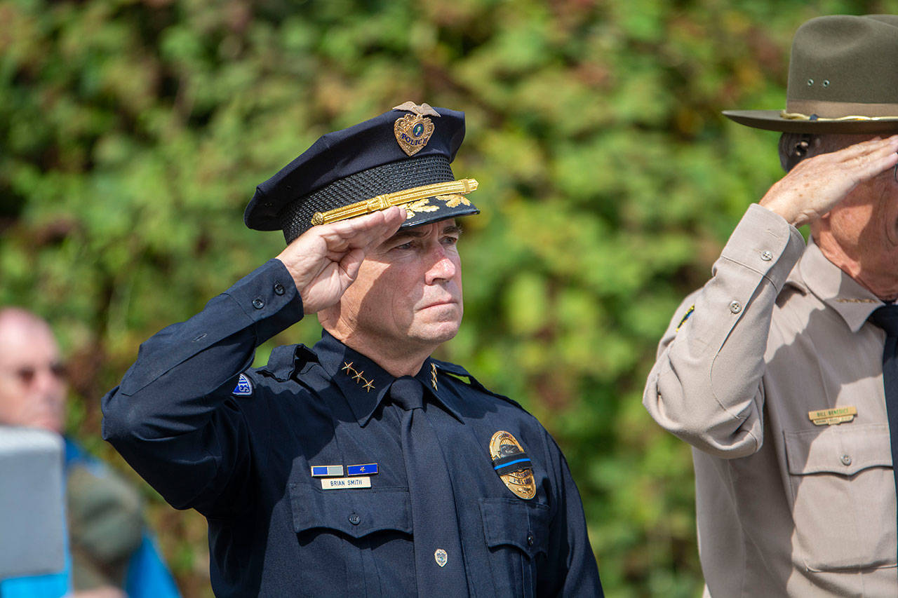 Port Angeles Police Chief Brian Smith salutes as the Grand Olympics Chorus sings the national anthem during a ceremony in Port Angeles honoring public safety officials on the 18th anniversary of the 9/11 terrorist attacks Wednesday. (Jesse Major/Peninsula Daily News)