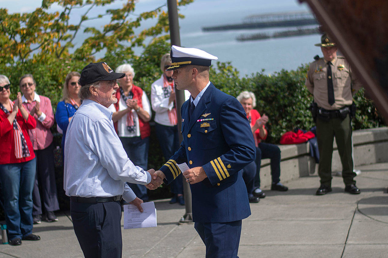 Even organizer Alan Barnard, left, shakes hands with U.S. Coast Guard Air Station Port Angeles Executive Officer Cmdr. Scott Austin during a ceremony in Port Angeles honoring public safety officials on the 18th anniversary of the 9/11 terrorist attacks Wednesday. (Jesse Major/Peninsula Daily News)
