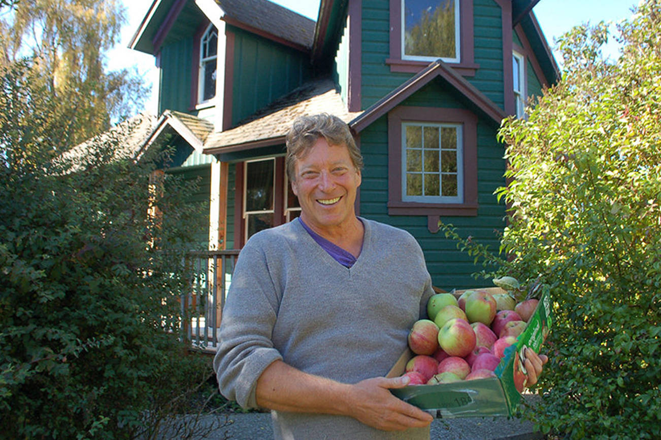 Mark Schwartz, host of Williams Manor and organizer of Applestock, poses in front of the manor with some of the apples from the orchard on the property in 2018. Sequim Gazette file photo