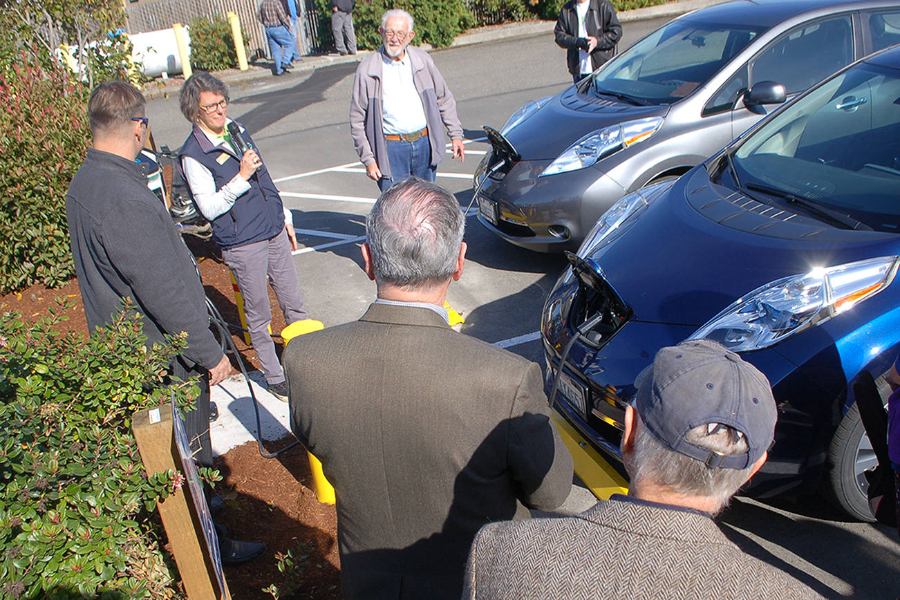 Sequim public works department resource manager Ann Soule, second from left, talks to the crowd after Eric Smith, left, and Walter Wielbicki, third from left, officially started charging their cars as the first two customers of the city’s new electric vehicle charging station at the old PUD substation at 410 E. Washington St. on Oct. 11. Sequim Gazette photo by Conor Dowley