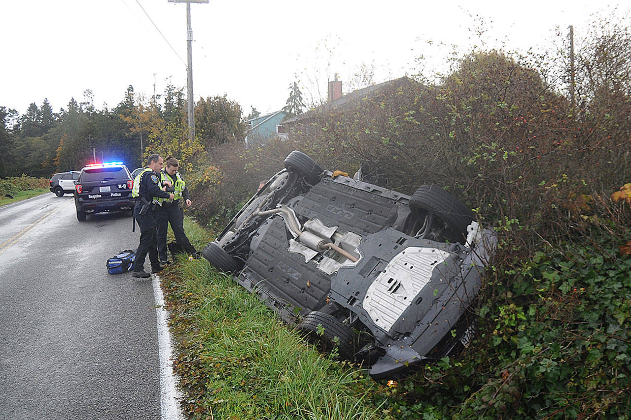 Sequim Police officers and Clallam County Fire District 3 personnel respond to a single-vehicle roll-over on West Sequim Bay Road Monday morning. At about 10:45 a.m., emergency responders extricated the driver who didn’t appear to sustain injuries, police officer Paul Dailidenas said. Cause of the incident is under investigation, he said. Sequim Gazette photo by Michael Dashiell