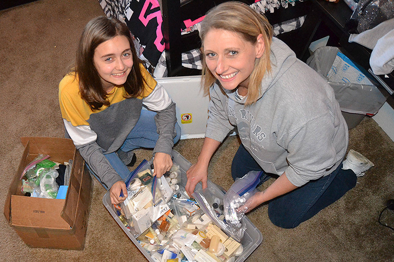 River Jensen, left, continues to gather toiletries with her mom Anna to create bags for in-need people this holiday season. Anna said for they used to wait to sort them but they received so many donations that it took them more a week to sort and bag. Sequim Gazette photo by Matthew Nash