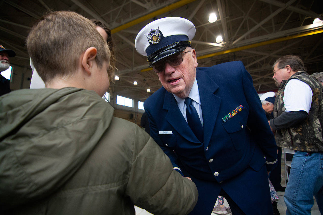 Richard Fleck of the Coast Guard Auxillary welcomes a young boy to the Veterans Day ceremony at U.S. Coast Guard Air Station/Sector Field Office Port Angeles on Monday. (Jesse Major/Peninsula Daily News)