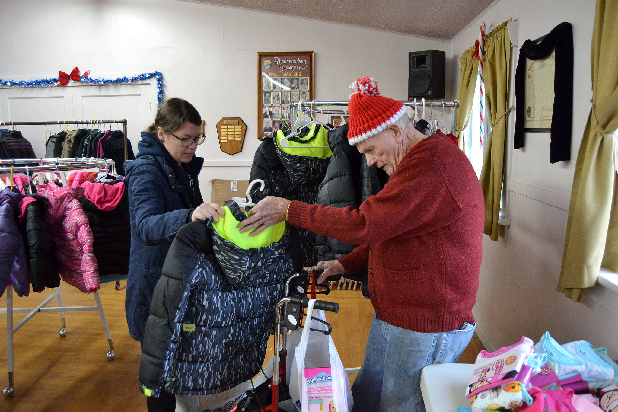 At last year’s Toys for Sequim Kids, Amber Ahrens of Sequim inspects a coat with volunteer Jack Keith. Organizers said last year’s event helped more than 350 children receive toys, games, clothes and more for Christmas. Sequim Gazette file photo by Matthew Nash