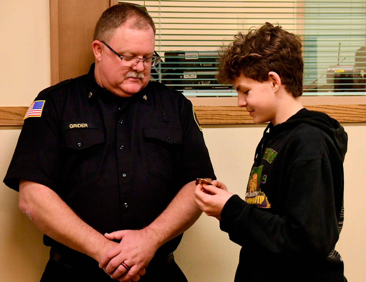 Deputy Fire Chief Justin Grider has his badge pinned on by his son Charlie on Nov. 19 at the Clallam 2 Fire Rescue board meeting. Submitted photo
