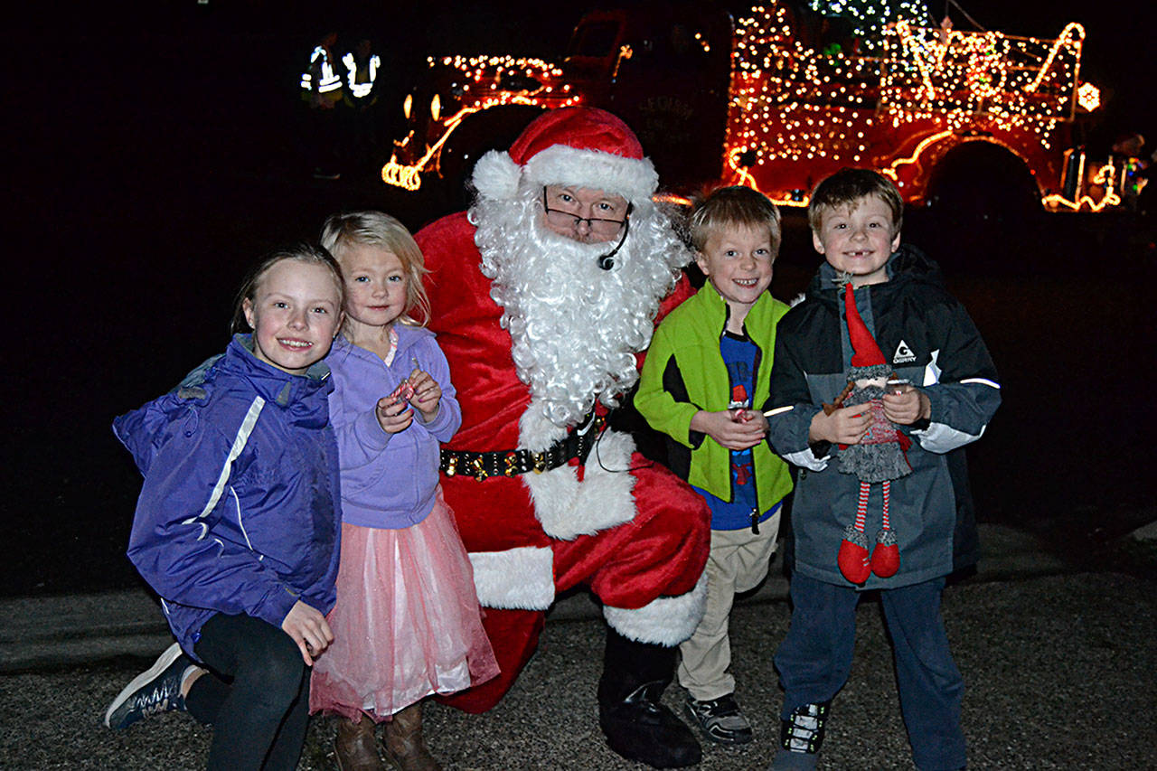 As part of Santa’s Toy and Food Brigade, Santa Claus (in similar stature to John Brygider) meets with Sequim siblings and cousins, from left, Grace Dormer, 9, Malta Bushy, 4, Sawyer Bushy, 6, and Bradly Dormer, 6, on Dec. 5 at Emerald Highlands. Santa and many volunteers traveled across Sequim Dec. 3-5 seeking donations for toys and food. Sequim Gazette photo by Matthew Nash