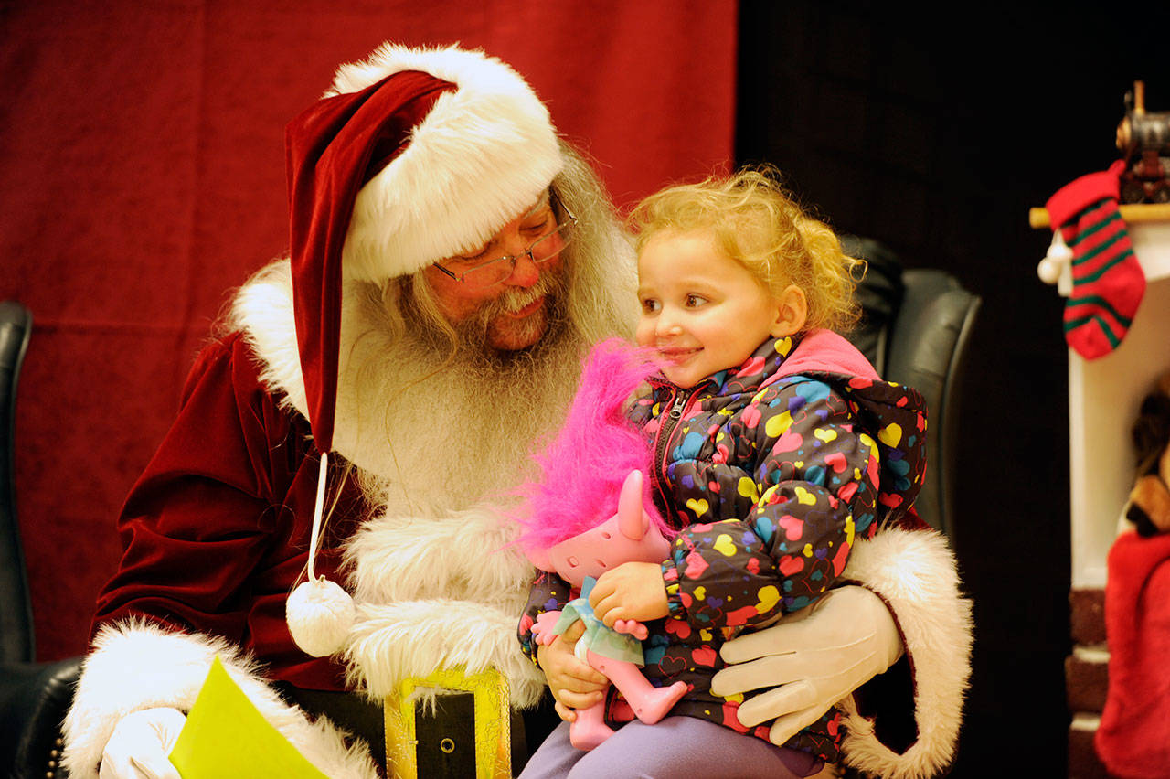 Above, Bayle Taylor, 2-and-a-half, of Sequim, shares a moment with Santa Claus (George Stuber) at the annual Breakfast With Santa event on Dec. 7. Proceeds from the event benefit Parenting Matters and the First Teacher Program.                                 Right, with a bit of a twist on the handprint keepsake, Sequim 5-month-old Charlotte Gatchet — with a bit of help from mom Karly and some of Santa’s helpers — gets a footprint at the annual Breakfast With Santa on Dec. 7. Sequim Gazette photos by Michael Dashiell