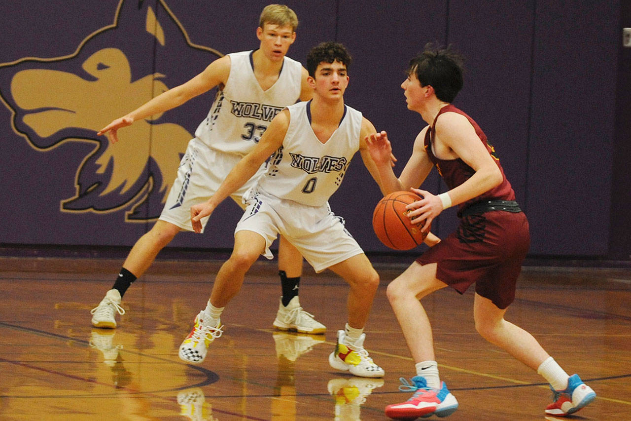Dallin Despain (0) and Stewart Duncan (33) defend as Kingston Buccaneers guard Christopher Russell looks to push the ball up the court in the second quarter of the Sequim Wolves’ 49-48 win over the Buccaneers on Dec. 11. Sequim Gazette photo by Conor Dowley
