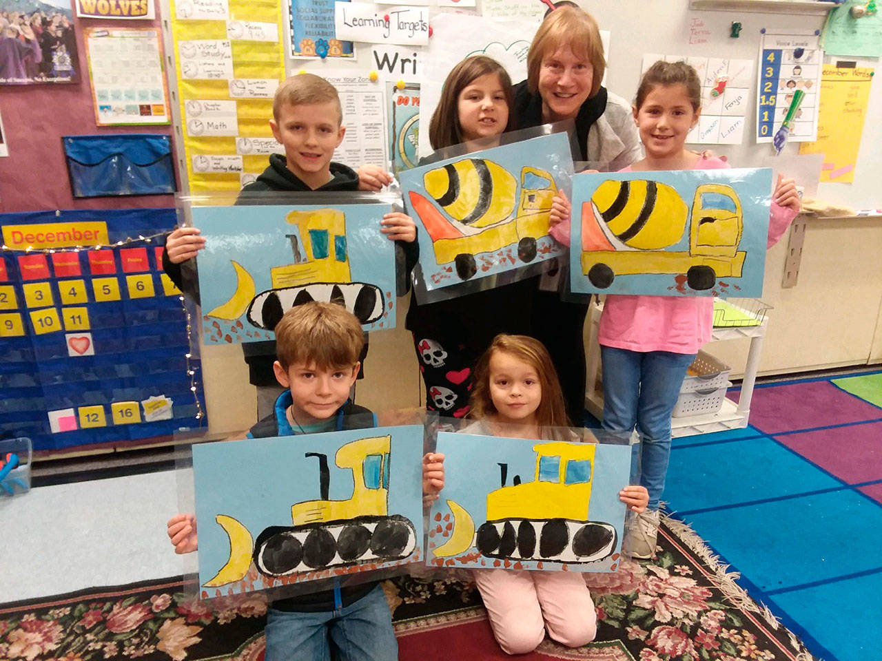 First-graders from Christine MacDougall Danielson’s class create artwork inspired by the Fir Street construction project to make placemats for school board directors. Pictured are (back row, from left) Aden Uhlig, Corinne Piersoll, MacDougall Danielson and Fenja Johnson, with (front row, from left) Makai Garten and Evelyn Moose. Photo by Patsene Dashiell