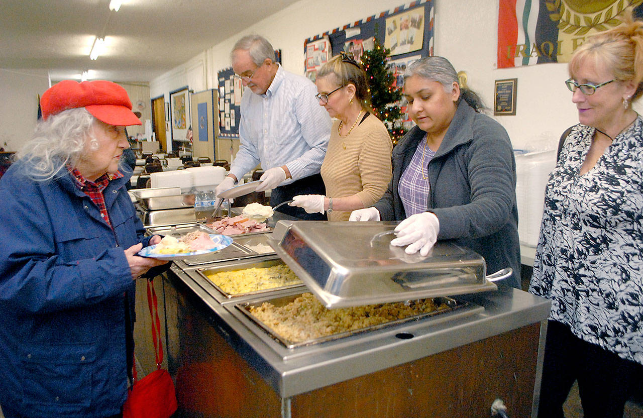 Julie Leigh of Port Angeles, left, is served a meal by volunteers, from left, Meil Gamroth, Katherine Vollenweider, Raman Khela and Vicki Shamp during a Christmas dinner at Sequim VFW Post 4760 on Christmas day. The free community meal was hosted by the VFW with assistance from Sun Taxi and Kettel’s 76. Photo by Keith Thorpe/Olympic Peninsula News Group
