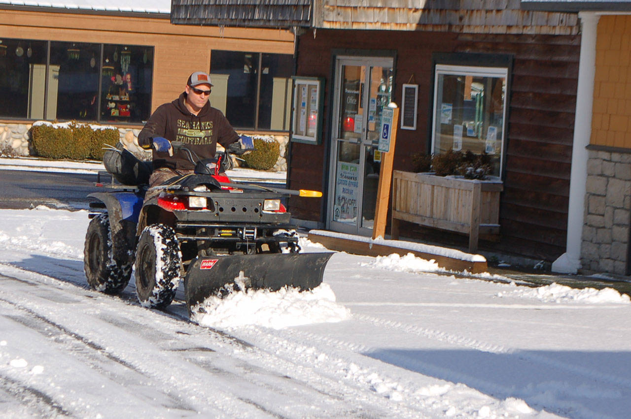 David Silliman of Simply Beautiful Builders clears the parking lot at 213 E. Washington St. with his ATV-mounted snowplow on Jan. 14. “I can get into a lot of places other plows can’t,” Silliman joked. Snowfall on Jan. 15 canceled and postponed a number of community events and forced closure of Sequim schools. Sequim Gazette photo by Conor Dowley