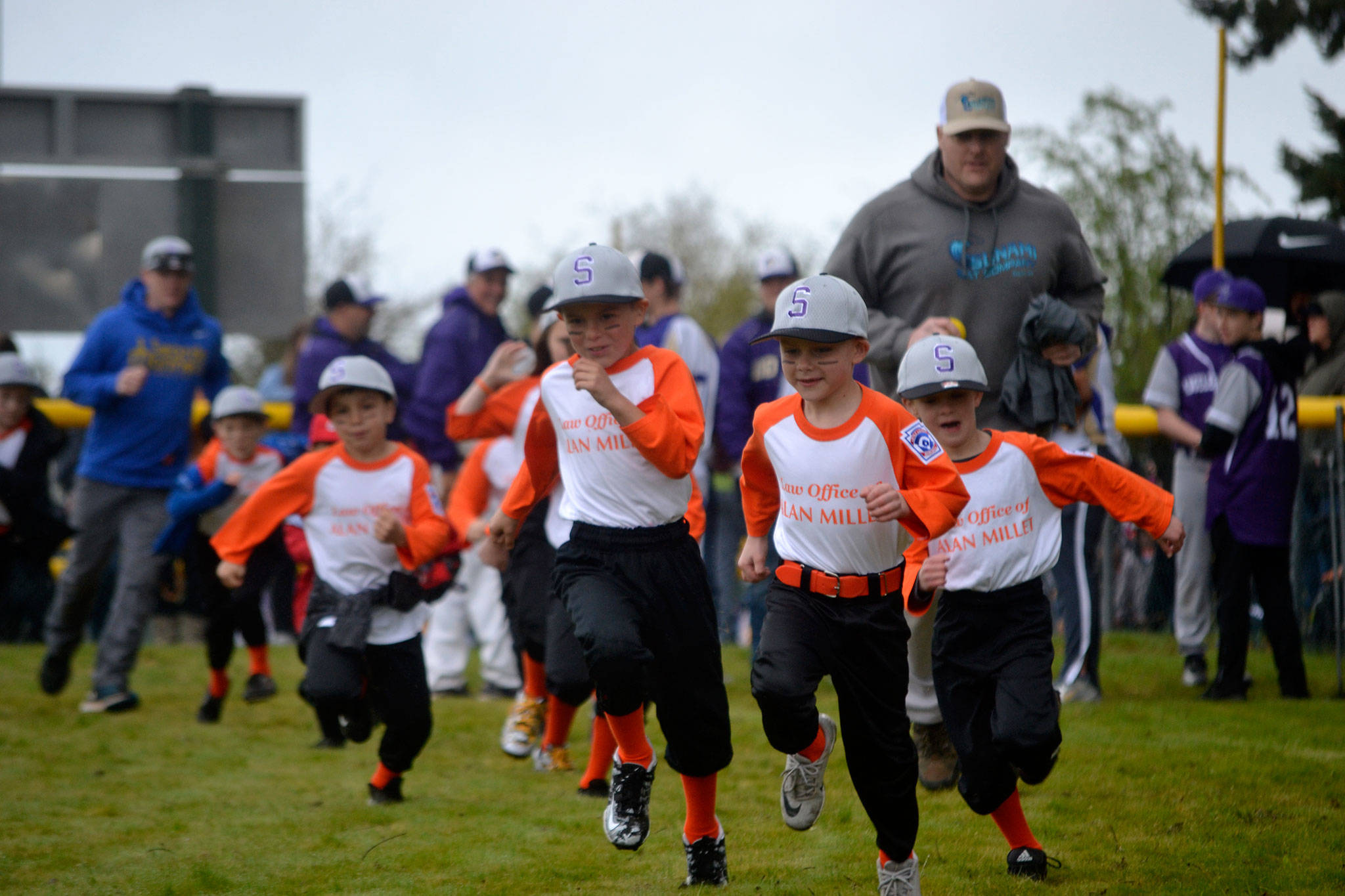 Players and coaches for the co-ed team of The Law Office of Alan Millet storm the field during the Player Procession at Sequim Little League’s Opening Day in April 2019. Sequim Gazette file photo by Matthew Nash