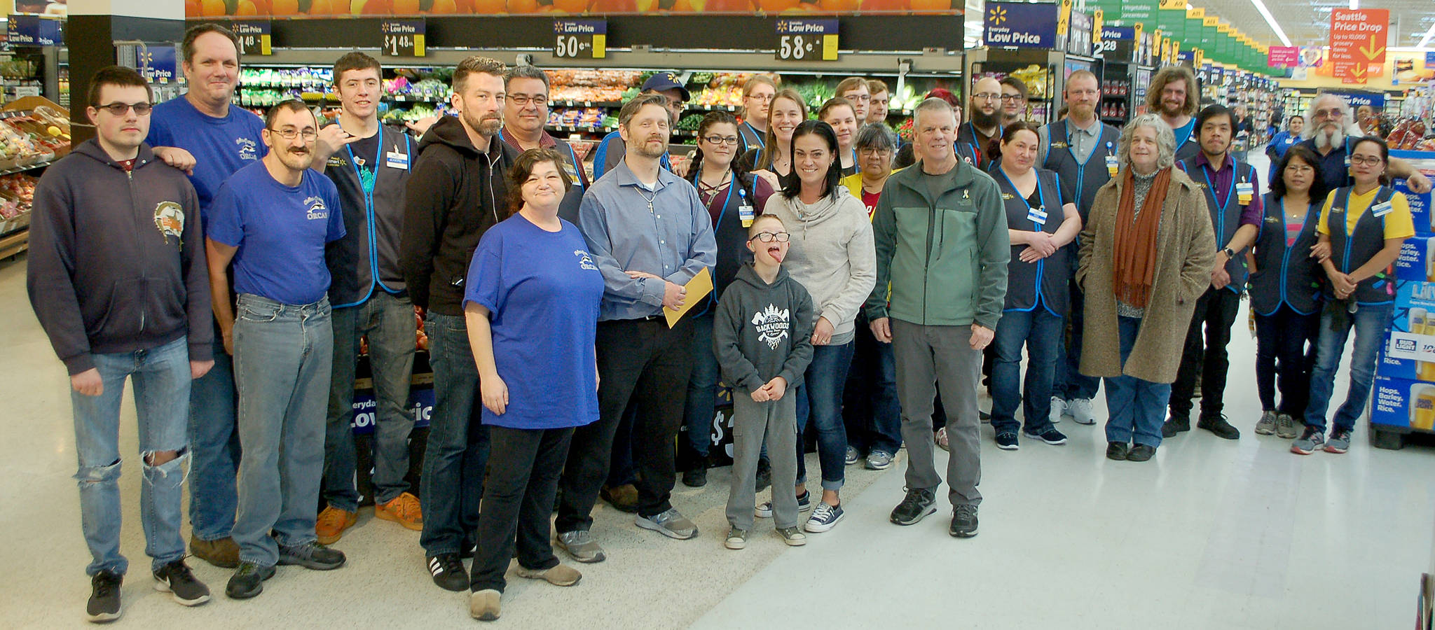 Members of the Clallam County Special Olympics group (left) and Catherine McKinney of Clallam County Mosaic (sixth from right) stand with employees of the Sequim Walmart as they receive donations from Rob Nichols (eighth from left) of the Knights of Columbus from the Tootsie Roll Drive fundraiser in November. Sequim Gazette photo by Conor Dowley