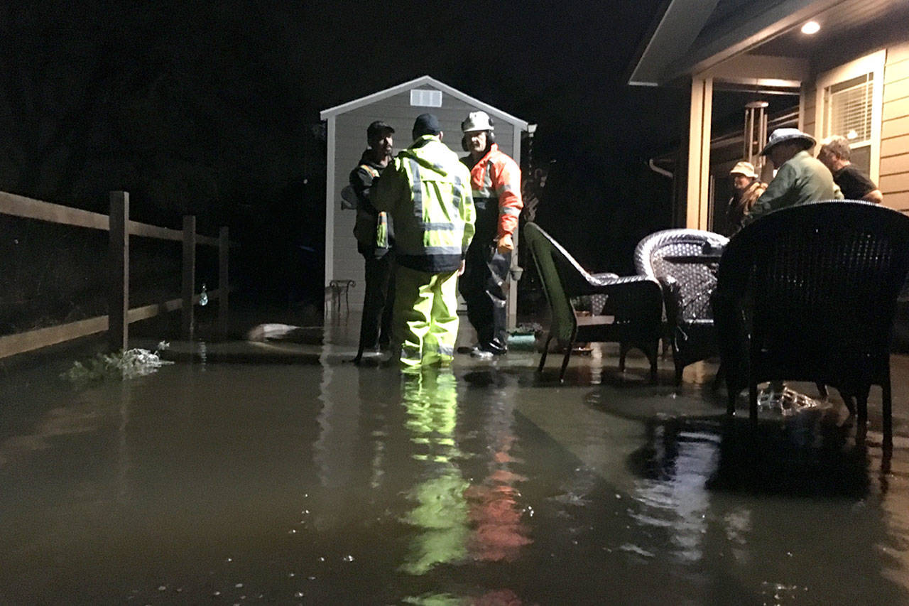City of Sequim staff consult late on Feb. 6 about options to resolve flooding issues off Rolling Hills Way in Sequim. Crews brought in a pump and sand bags to take out and keep water out of the home’s crawlspace. Sequim Gazette photo by Matthew Nash