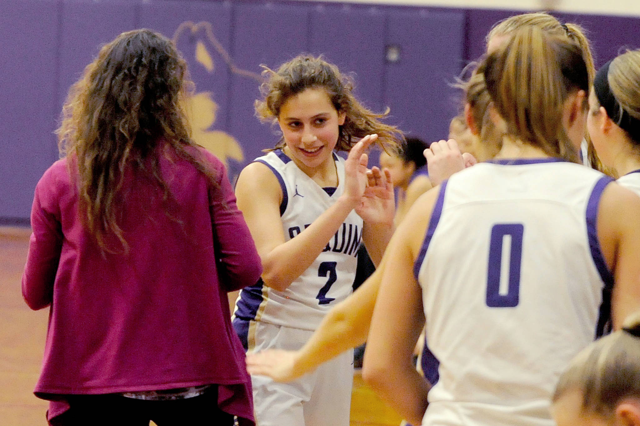 Sequim Wolves seniors Hope Glasser (0) and Jessica Dietzman (2) celebrate with head coach Linsay Rapelje (left) and their teammates after coming off the court to a standing ovation in the final minute of the Wolves’ 92-22 district playoff win over the Foster Bulldogs on Feb. 12. It was the final home game the seniors will play, with Sequim slated to head out on the road for the remainder of the tournament. Sequim Gazette photo by Conor Dowley