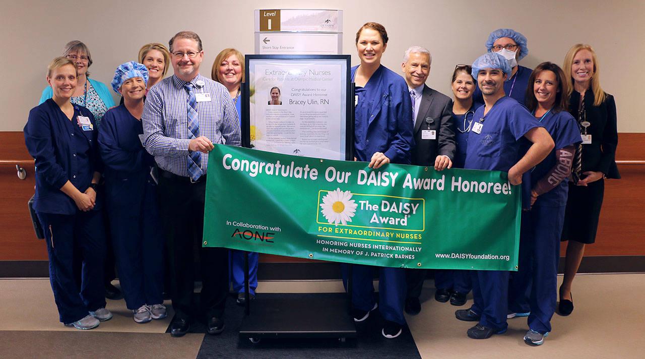 Registered nurse Bracey Ulin (front row, fourth from left) receives her DAISY Award for Extraordinary Nurses honor from chief nursing officer Ralph Parker (third from left). Photo courtesy of Olympic Medical Center