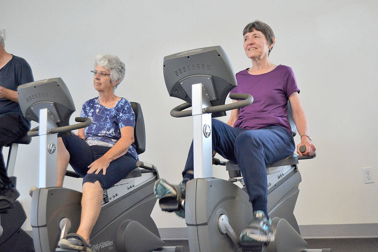 Linda Flores of Port Angeles, left, and Mary Farley of Sequim cycle at the YMCA of Sequim during a workout with the Exercise and Thrive program. The three Olympic Peninsula YMCA facilities are closing through March 31. Sequim Gazette file photo by Matthew Nash