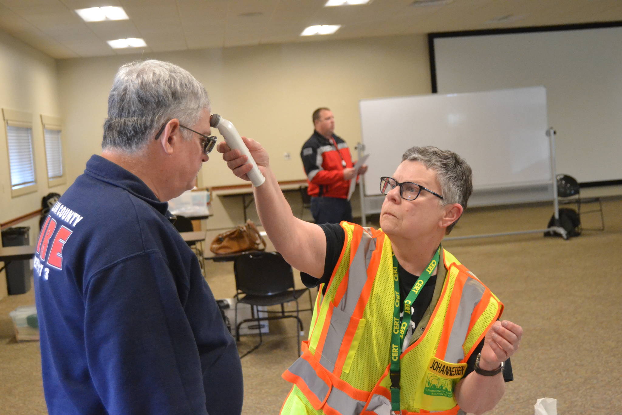 Linda Johannessen, Community Emergency Response Team No. 9 member, checks the temperature of firefighter/EMT Jeff Nicholas before he enters the Emergency Coordinating Center in the Guy Cole Event Center on March 23. Sequim’s response to COVID-19 will work out of the facility for the immediate future. Sequim Gazette photo by Matthew Nash