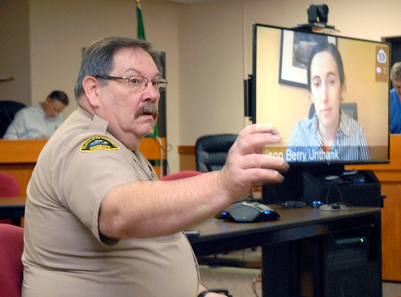Clallam County Undersheriff Ron Cameron, left, fields questions as Dr. Allison Berry Unthank, the county’s public health officer, delivers COVID-19 updates through a video link from her home on March 25 at the Clallam County Courthouse in Port Angeles. Photo by Keith Thorpe/Olympic Peninsula News Group