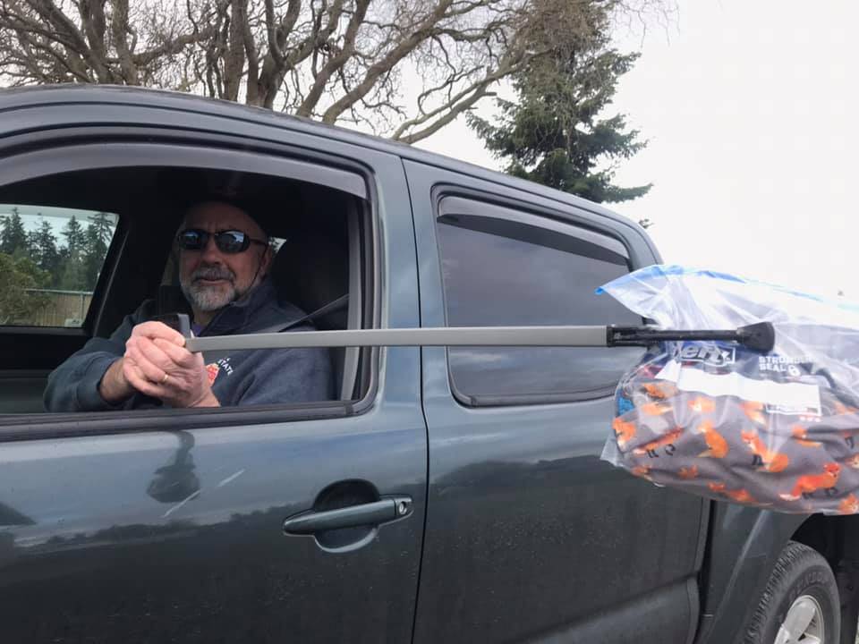 Jim Stoffer, one of the organizers of Sequim Face Masks Challenge, uses social distancing to pick up some face masks from Monica Dixon. Photo courtesy of Jim Stoffer