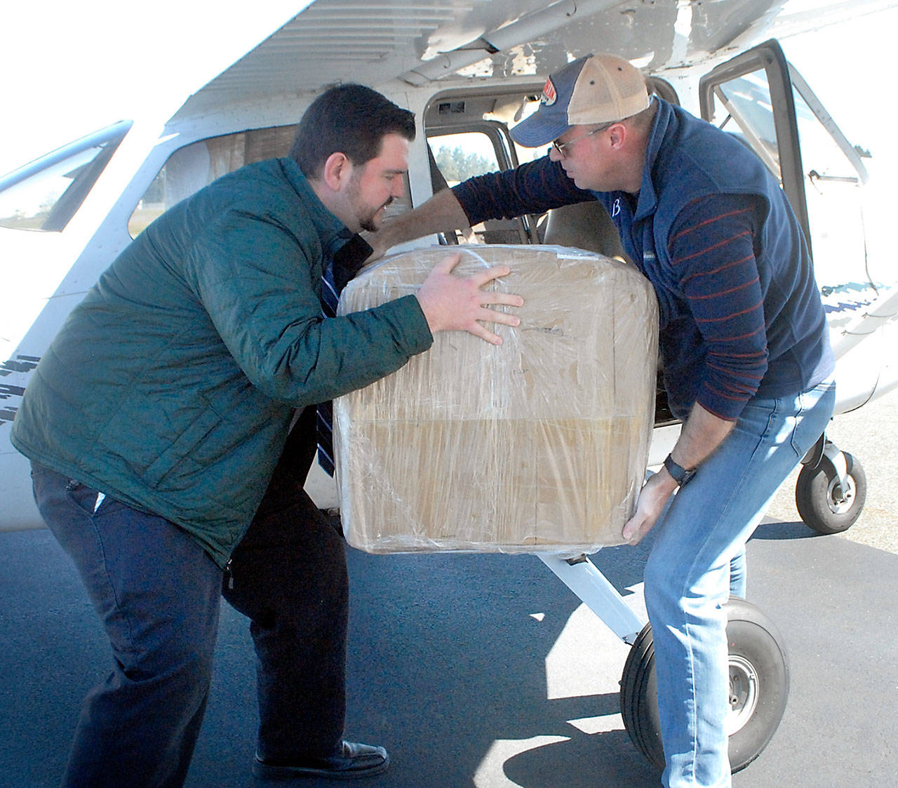Bastian Hardtke, purchasing manager at Olympic Medical Center, left, takes a box from Boeing Employee’s Flying Association member Doug Weller of Seattle after two aircraft containing 30,000 surgical masks for the hospital arrived on Thursday, APril 16, at William R. Fairchild International Airport in Port Angeles. Photo by Keith Thorpe/Olympic Peninsula News Group