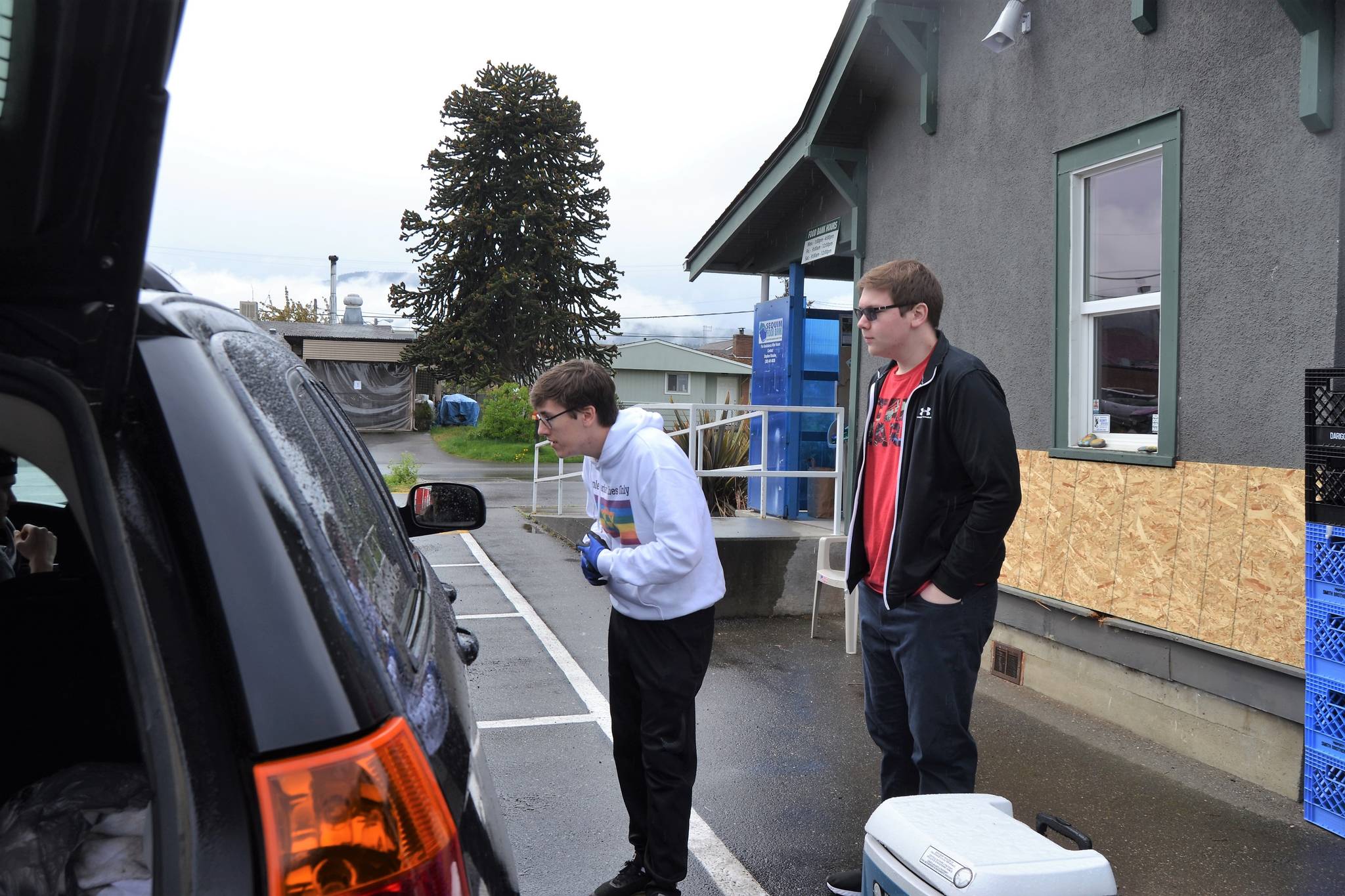 Erik Holtrop and Caden Habner help a resident with milk and meat at the Sequim Food Bank. The two became better friends through volunteering there, and Holtrop encourages people to call or visit if they need help because the facility has “plenty of food.” Sequim Gazette photo by Matthew Nash