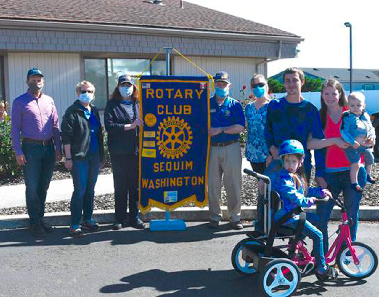 Members of the Rotary Club of Sequim (from left, Jason Bausher, Rochelle McHugh, Pat Zane and Jim Jones) join physical therapist Cherry Bibler in presenting a Rifton adaptive tricycle to 8-year-old Jorden Topham, pictured here with parents Chris Parizo and Anna Gloor, and brother Noah. Photo by Doug Schwarz
