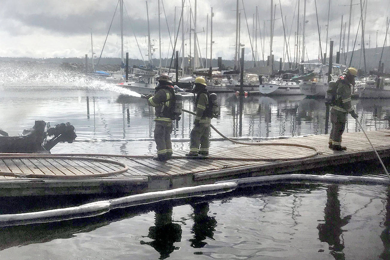 Clallam County Fire District No. 3 firefighters Chad Cate, Colton McGuffey and Bo Pinnel fight a boat fire at John Wayne Marina Saturday morning. Photo courtesy of Clallam County Fire District No. 3
