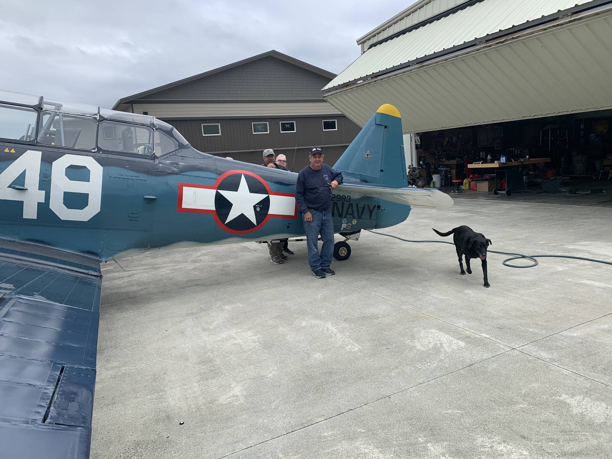 John Johnson, on left, with his wife Susie and crew chief Dave Richardson, and dog Kona, stand next to John’s T-6 Texan that he and Richardson will travel with on an aircraft to Hawaii and fly to commemorate the end of World War II 75 years ago. Photo courtesy of Kaye Gagnon