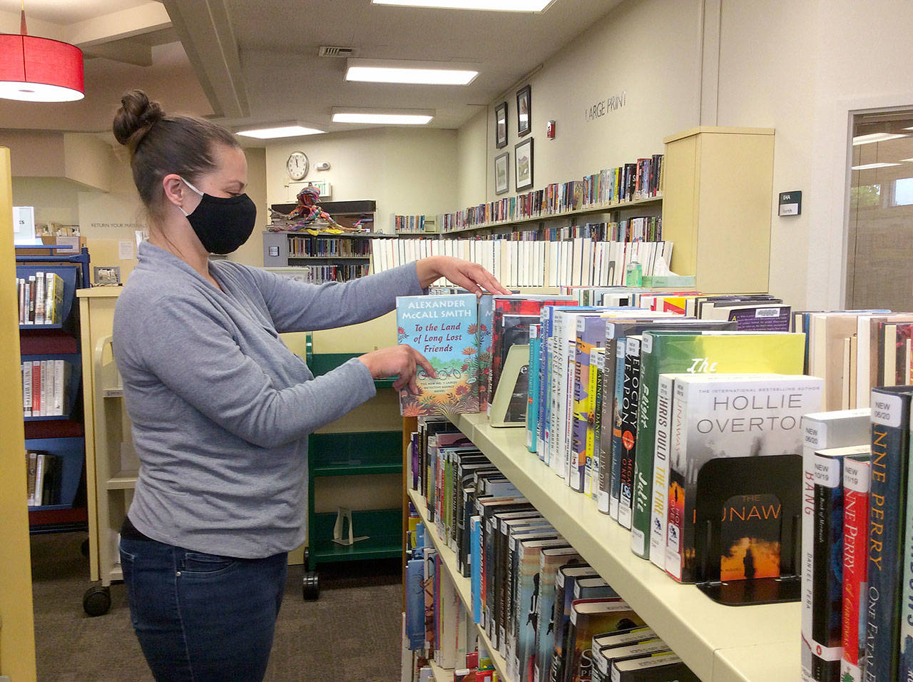 Annie Brooker sorts through books at the Sequim Library. Through libraries are closed to the public, NOLS staff are able to help readers find new books through a variety of services. Photo courtesy of North Olympic Library System