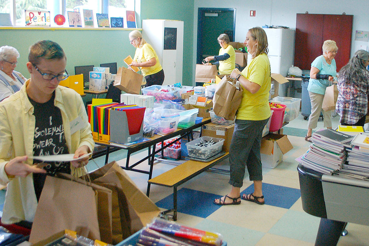 Janet Gray (third from right) and volunteers fill bags with school supplies for students at the 2019 Sequim Back To School Fair. This year’s fair is set for Aug. 29. With a number of health restrictions in place, organizers have changed the event to a “drive through” model. Sequim Gazette file photo by Conor Dowley