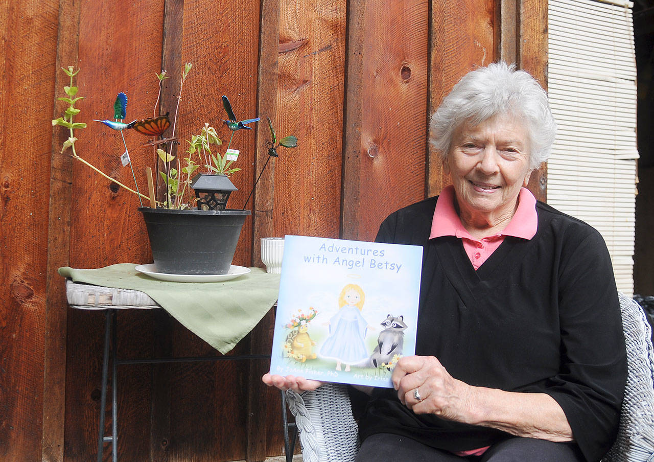 Sequim author JoAnn Fisher displays her first book, “Adventures with Angel Betsy.” Illustrations (at left) are by Ukranian artist Irina Litvin. Sequim Gazette photo by Michael Dashiell