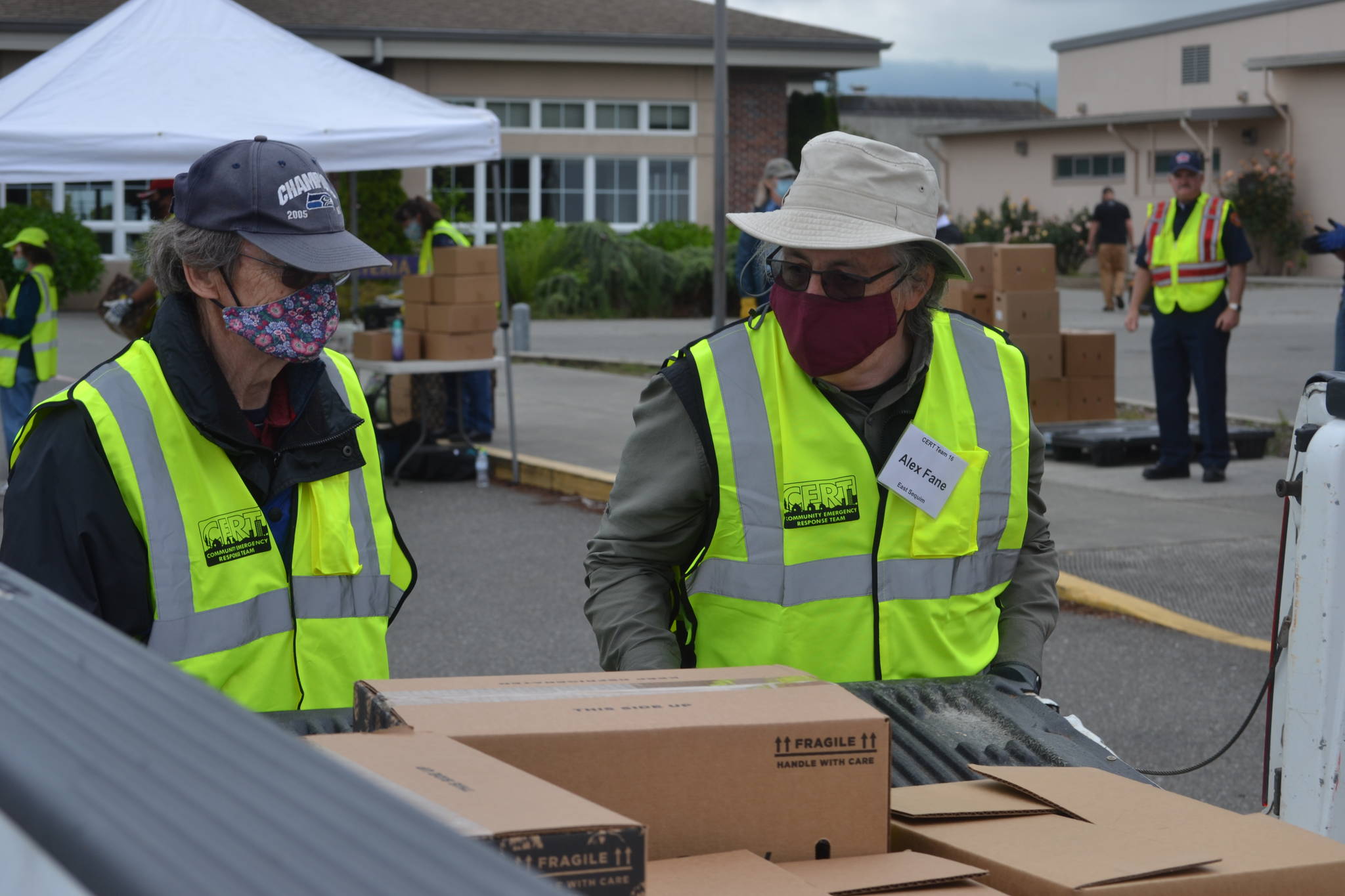 Volunteers Bruce Leigh and Alex Fane with Community Emergency Response Teams (CERT) put food boxes in a truck bed on June 10 at Sequim High School. The program moves to Trinity United Methodist Church from 11 a.m.-2 p.m. Wednesdays starting Aug. 26. Sequim Gazette photo by Matthew Nash
