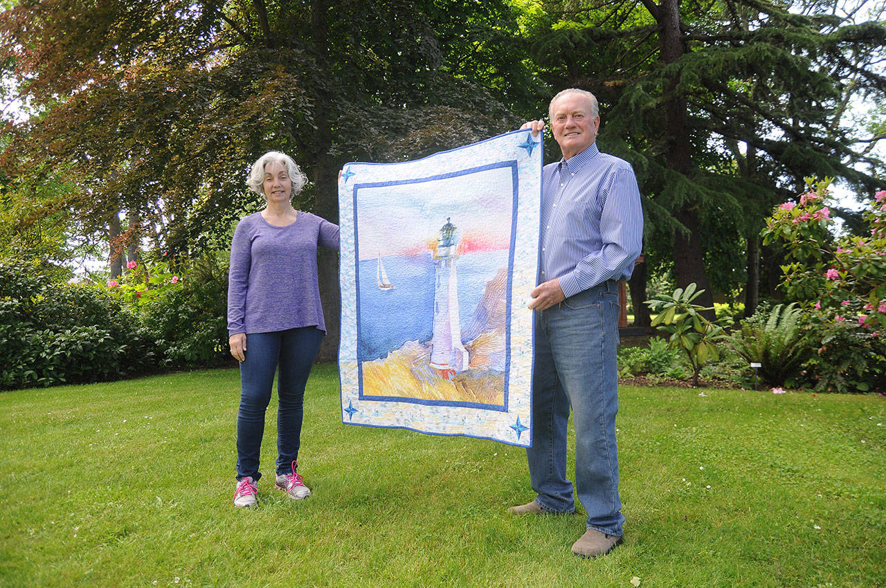 Quiltmaker Dory Miller of Crazy Horse Quilting and 2020 Sequim Bay Yacht Club commodore Jerry Fine display a quilt up for raffle, with proceeds going to Volunteer Hospice of Clallam County. Tickets are $5 each or six for $25. Organizers of the yacht club’s annual Reach and Row for Hospice recently announced the cancellation of the event, and are urging those looking to continue support of the effort to purchase raffle tickets or make a tax-deductible donation. Sequim Gazette photo by Michael Dashiell