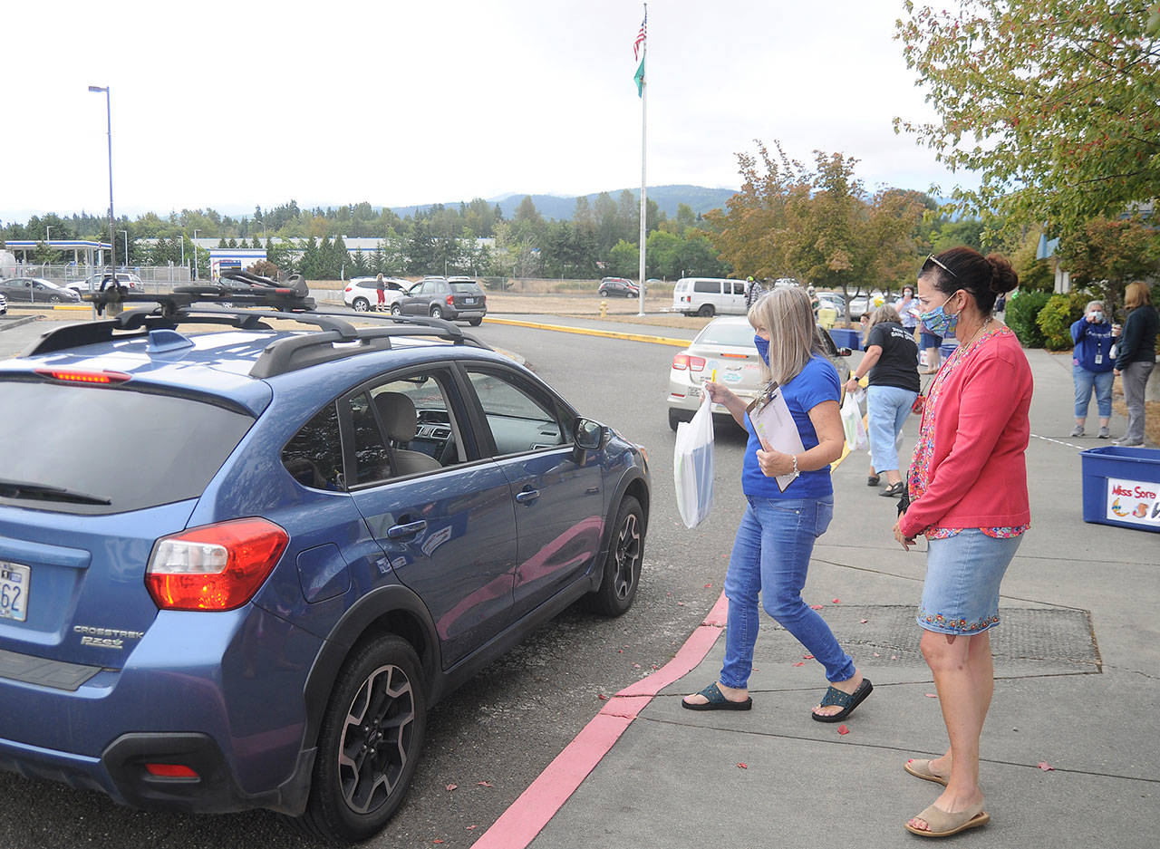 Third-grade teacher Sheri Burke, center, and reading specialist Natalie Fortier hand out packets of school curriculum and materials at Greywolf Elementary School on Sept. 2, the first day of school for Sequim students. Sequim Gazette photo by Michael Dashiell
