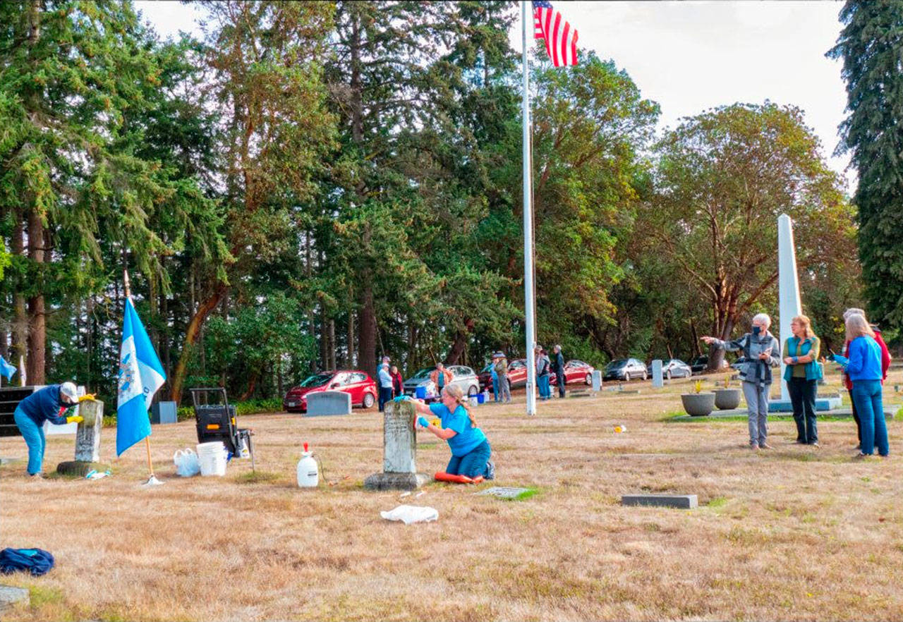 Members of the Michael Trebert Chapter of the Daughters of the American Revolution and Sequim Sunrise Rotary groups tend to headstones and plaques of veterans at Sequim View Cemetery last week. Photo by Bob Lampert
