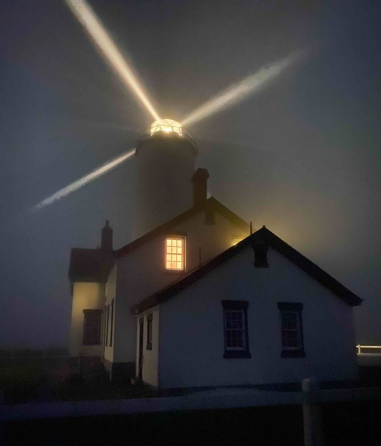 The New Dungeness Lighthouse, pictured here shining light through a thick fog, got some TLC this summer from volunteers. The light station’s museum and light tower remain closed to the public Photo by Ben Wasson