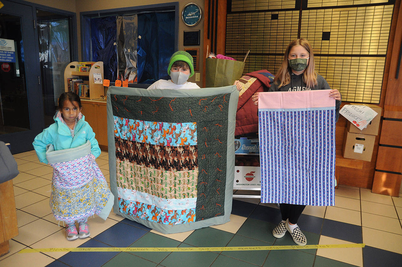 From left: Aaliyah Turner, Harley Bullington and Madison Wilkinson last week display some of the hand-crafted quilts and pillowcases made by Sequim volunteers for the trio and other fellow club members. Sequim Gazette photo by Michael Dashiell