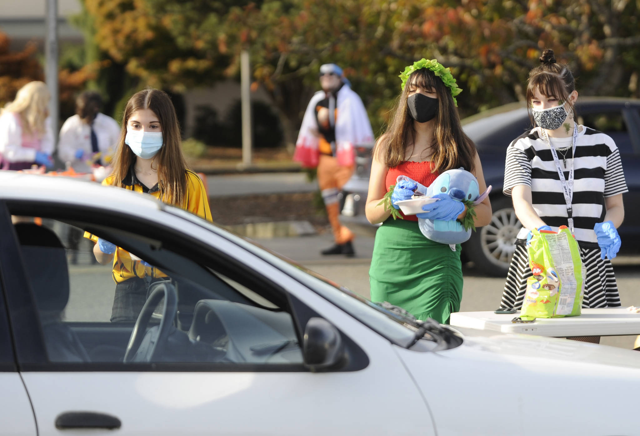 From left, Sequim High School students Alliyah Weber, Christina Caples and Delaney Nucci hand out candy at SHS’s drive-thru Halloween event on Oct. 31.
