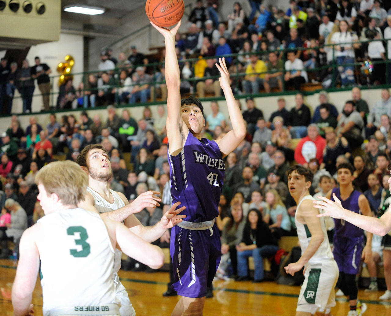 Sequim’s Isaiah Moore, center, puts up a shot over the Port Angeles defense in the Wolves’ 57-32 loss in February. State sport officials said the return of high school sports will be delayed by at least another month and all three prep seasons have been reduced by a week. Sequim Gazette file photo by Michael Dashiell