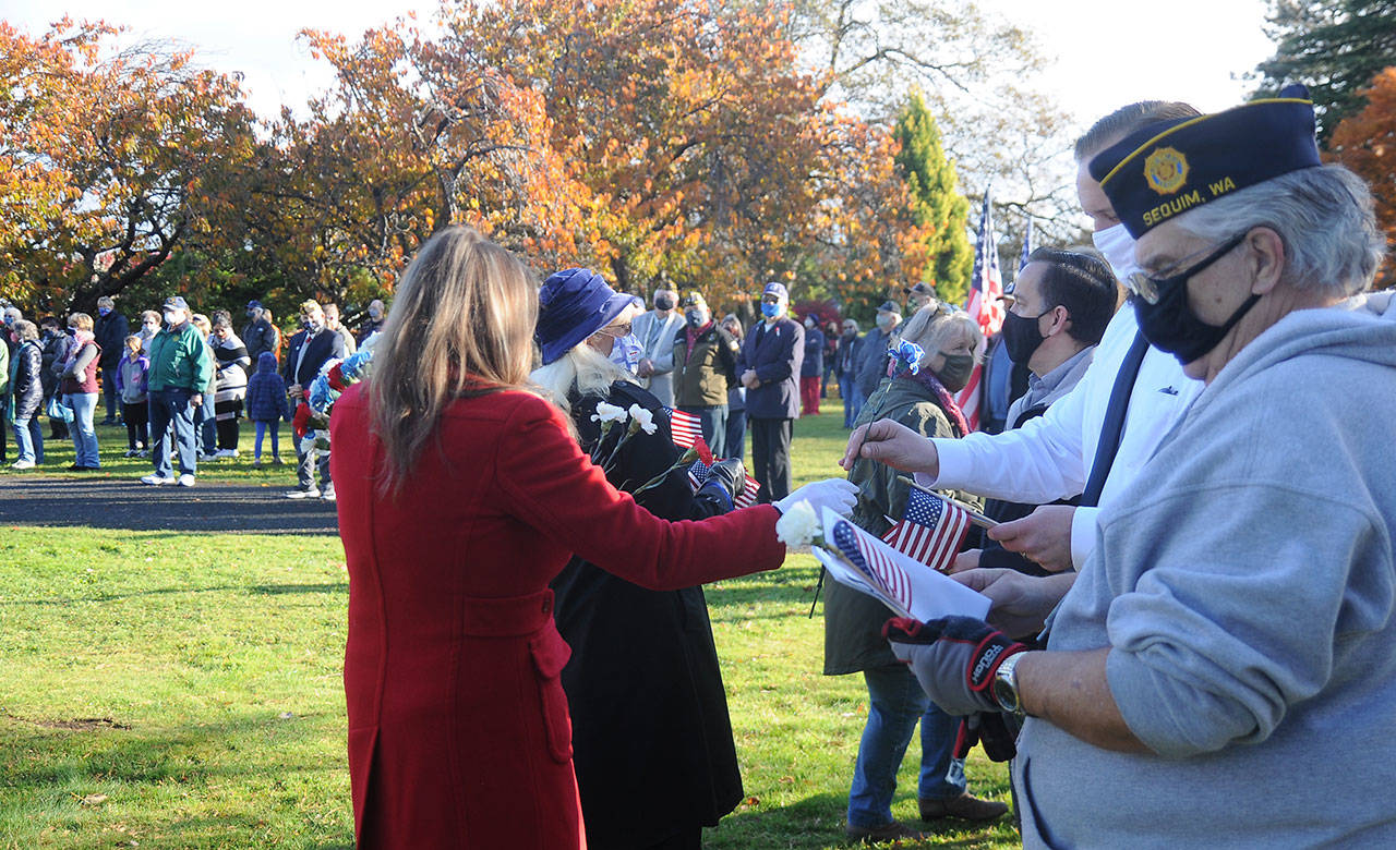 Members of the Daughters of the American Revolution-Michael Trebert Chapter hand out red, white and blue flowers to veterans and their families at Pioneer Memorial Park on nov. 11. Sequim Gazette photo by Michael Dashiell