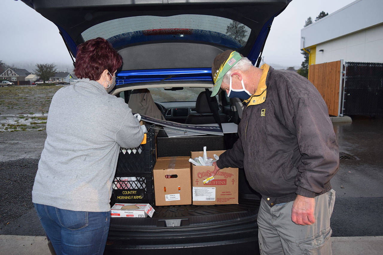 YMCA staff members Jaimie Giffen, left, and Virgil Hull load a car to deliver meals to students on Monday, Dec. 21. Photo by Erin Hawkins/Olympic Peninsula YMCA