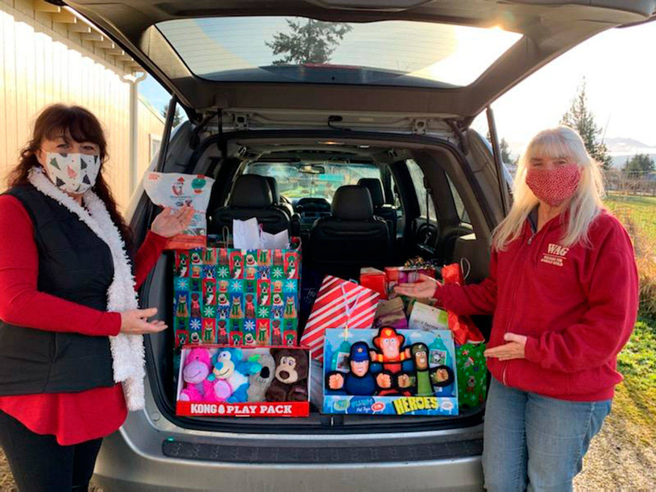 Welfare for Animals Guild president Barb Brabant, right, joins Julie Hatch of Kitsap Bank to accept a carload donation of gifts for WAG dogs. Submitted photo