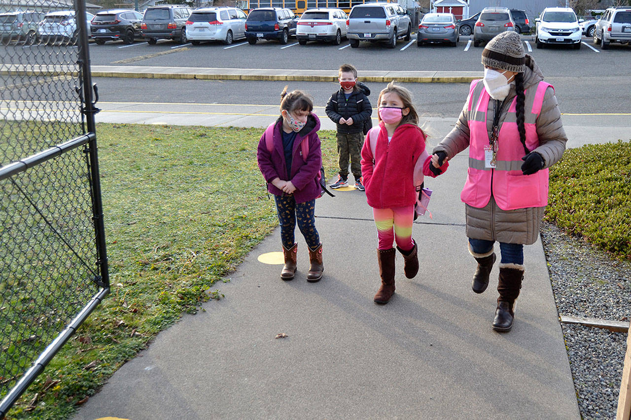 Paraeducator Monica Gonzalez brings Aislyn Gockerell to line up for her kindergarten class at Helen Haller Elementary on the first day back on Jan. 26 after months away from school due to COVID-19 concerns. Sequim Gazette photo by Matthew Nash