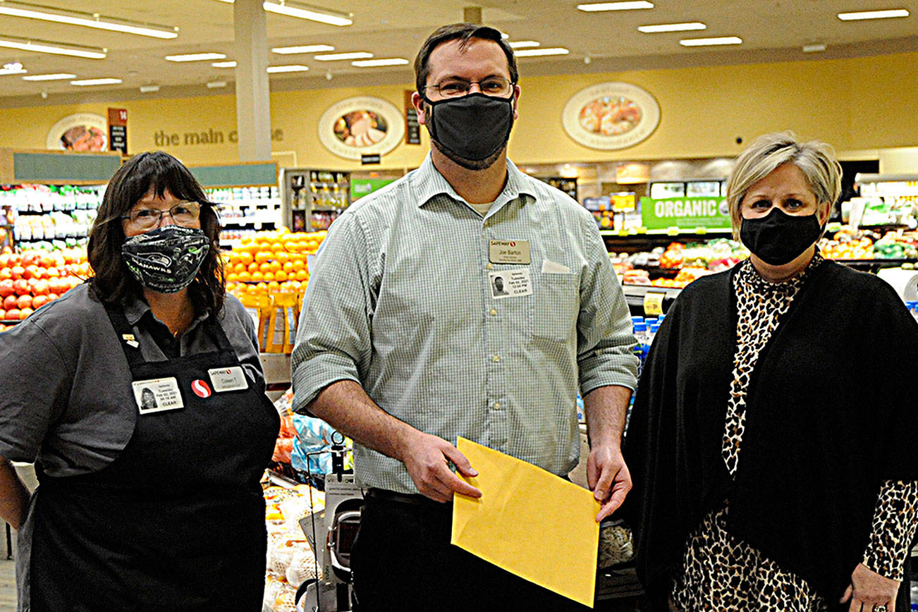 Sequim Safeway checker Colleen Tenneson and manager Joe Barton helped raised more than $87,000 from customer donations for the Sequim Food Bank fundraiser over November and December. Andra Smith, food bank executive director, on right, said donations will go towards gift cards, which she loves because “it allows families to choose and make their own nutritional decisions.” Sequim Gazette photo by Matthew Nash