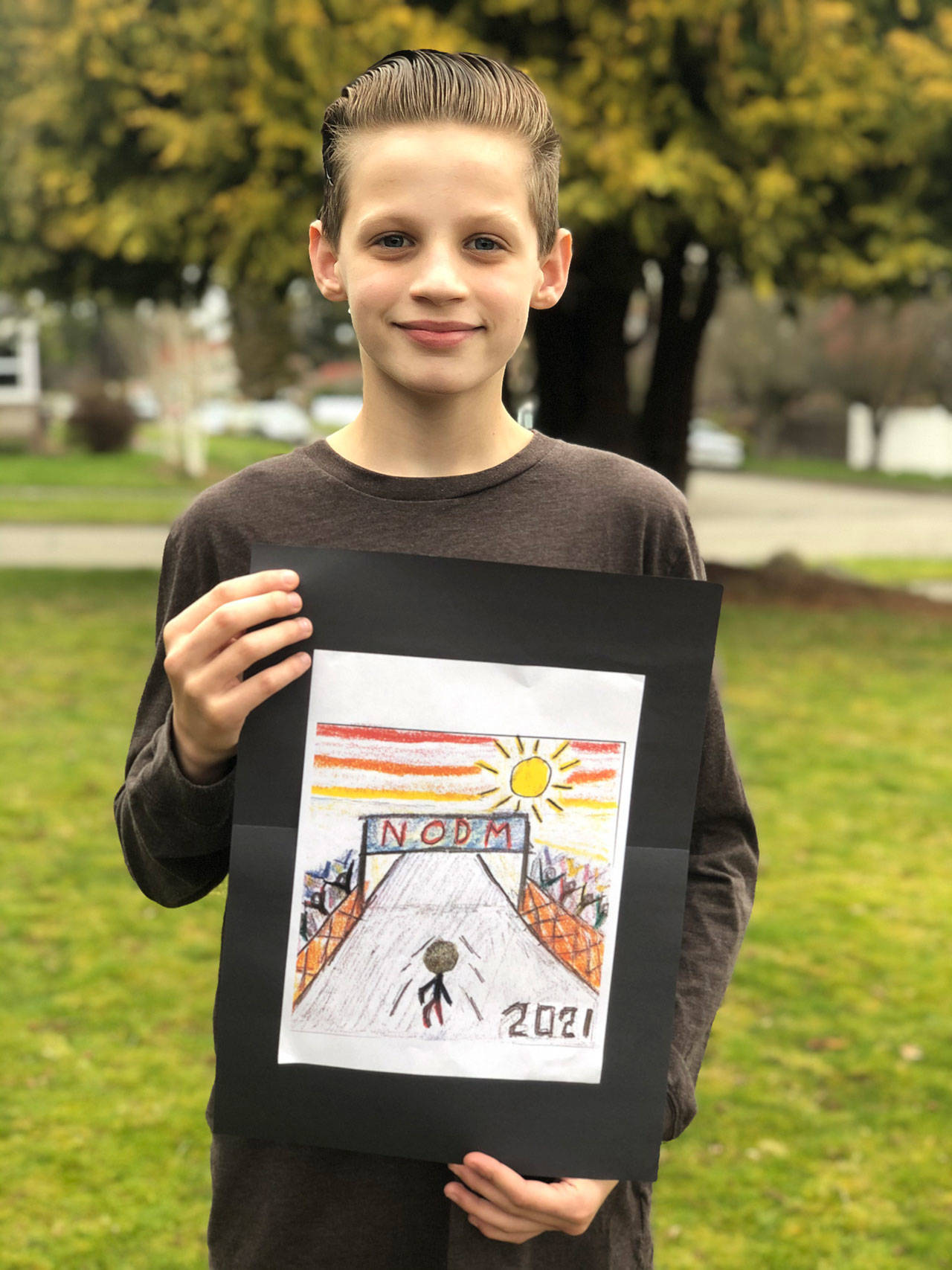 John Ruddell, a 12-year-old student at Dry Creek Elementary in Port Angeles, shows off his award-winning entry in the 2021 North Olympic Discovery Kids Marathon Medal Design Contest. Submitted photo